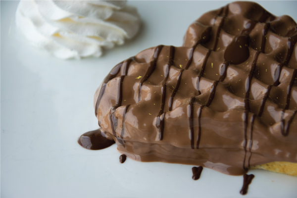 Photo of a heart waffle with chocolate sauce from Clay's dessert menu.