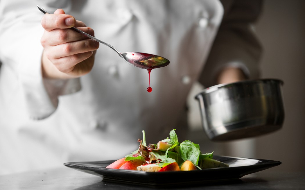 Image of chef drizzling sauce onto a food plate