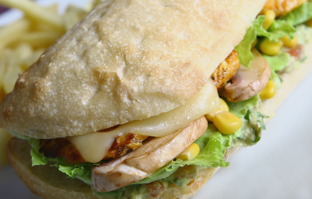 Photo of chicken ciabatta sandwich with grilled chicken strips, melted cheese, mushrooms, sweet corn, and lettuce from Clay restaurant's bites & wraps menu.