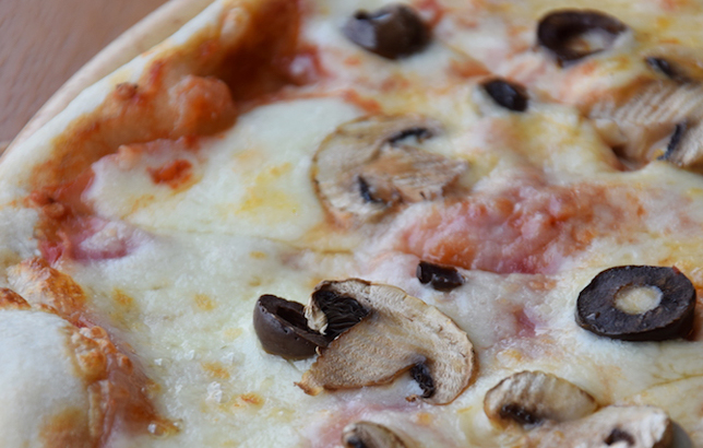 Image of Italian pizza with cheese, tomatoes, ham, mushrooms, and olives.