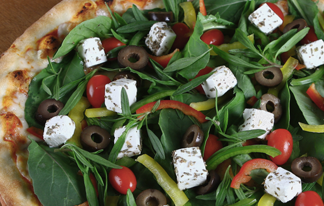 Image of Italian pizza with feta cheese, olives, cherry tomatoes, and rocket leaves.