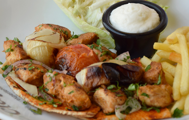 Image of a traditional Lebanese dish: chicken skewers with grilled vegetables and French fries.