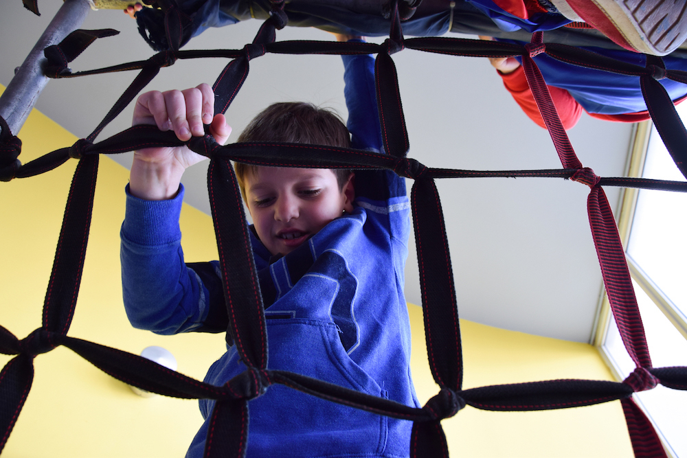 Image of a young boy climbing up the net during Clay restaurant's kids sports games event